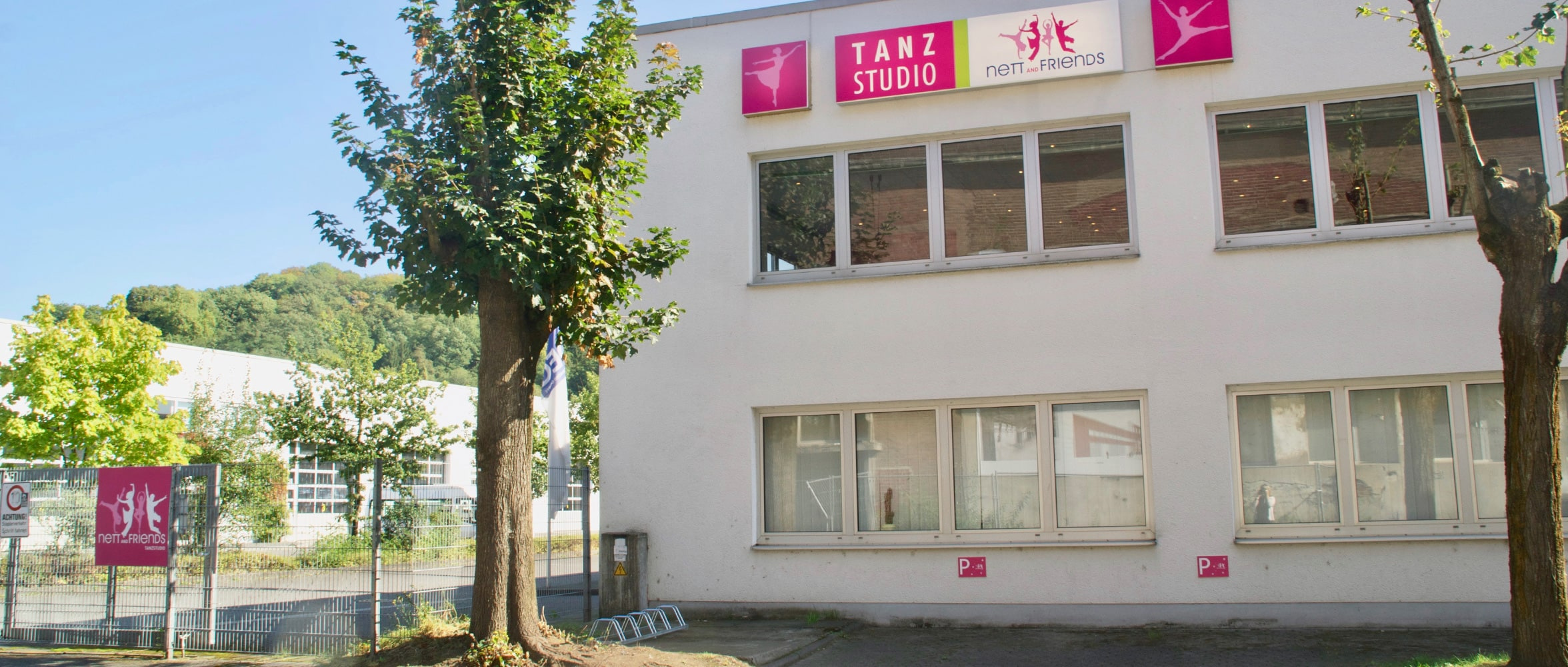 Außenansicht der Tanzschule Nett & Friends Siegburg – modernes Gebäude mit großem Logo und kostenfreien Parkplätzen direkt vor dem Studio.