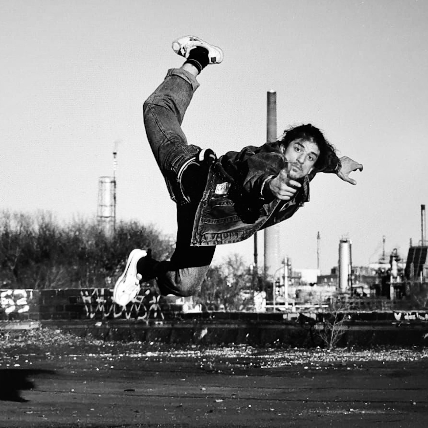 Samu Chourafa im Sprung in Bauchlage vor Industriegebäude – Urbaner Style und Ausdruckskraft im Breakdance